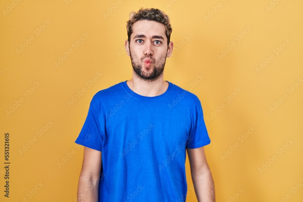 Hispanic man with beard standing over yellow background making fish face with lips, crazy and comical gesture. funny expression. Hispanic man with beard standing over yellow background making fish face with lips, crazy and comical gesture. funny expression.