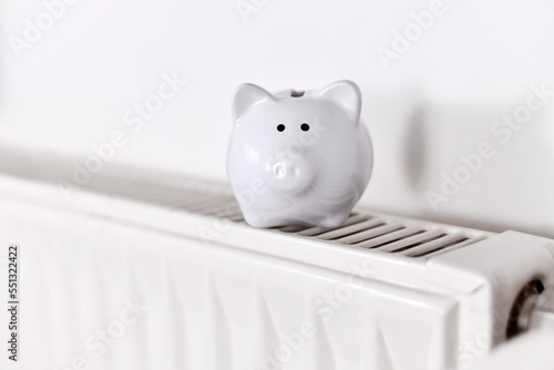 Concept for saving money for gas for heating with piggy bank on radiator with copy space