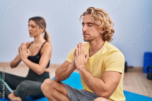Man and woman couple training yoga at sport center