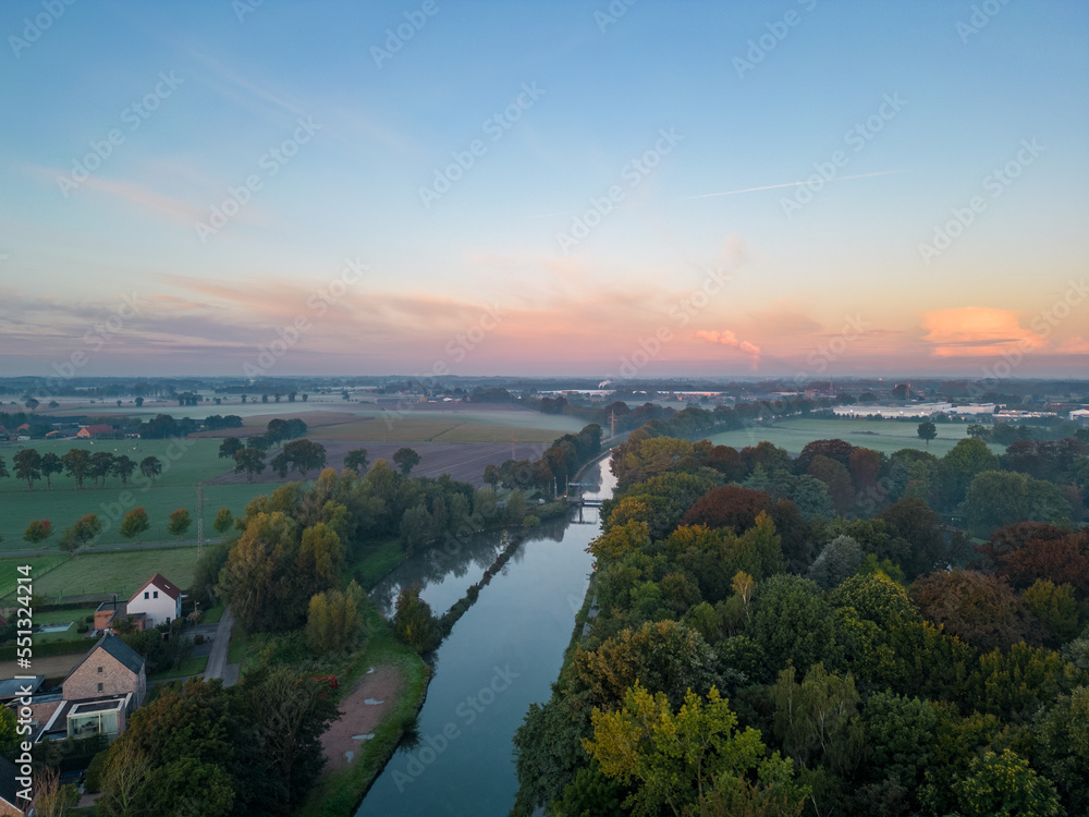 Panorama of dramatic and colorful sky over Fields, trees and River or canal from a drone during sunset or sunrise. High quality photo