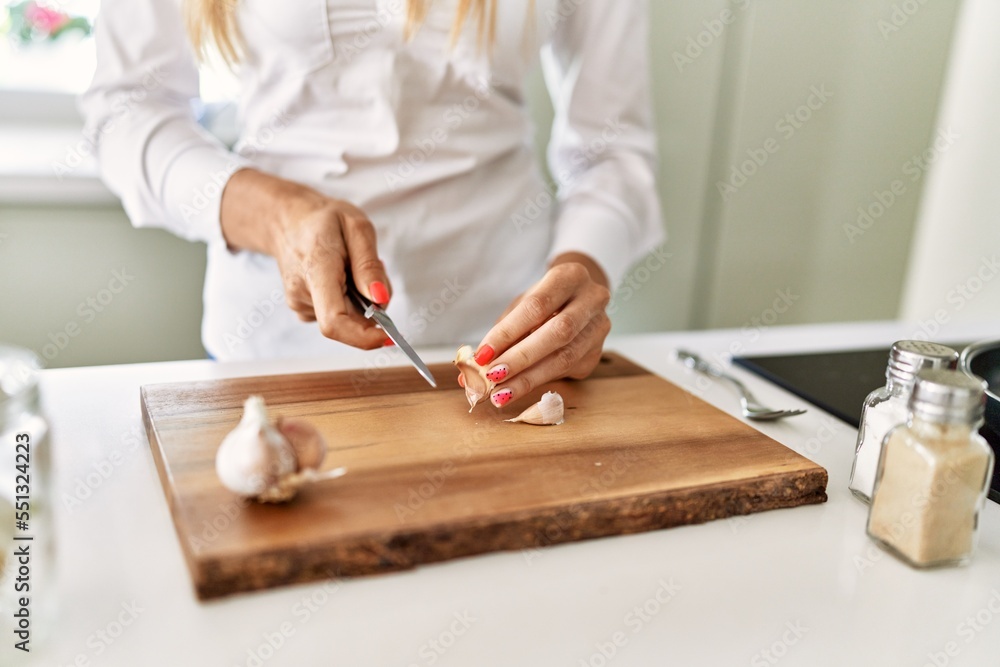 Young blonde woman cutting garlic at kitchen Young blonde woman cutting garlic at kitchen