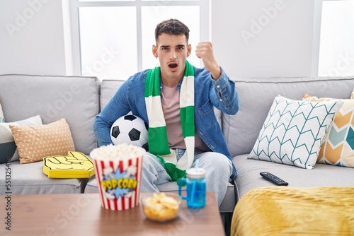 Handsome hispanic man holding ball supporting team annoyed and frustrated shouting with anger, yelling crazy with anger and hand raised © Krakenimages.com