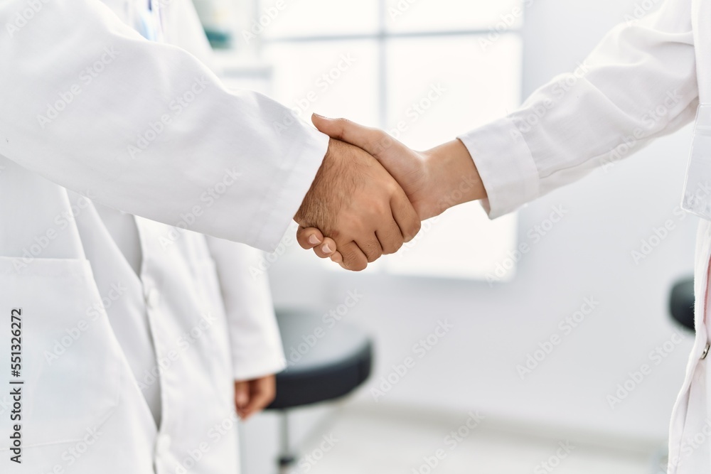 Man and woman wearing scientist uniform shake hands at laboratory Man and woman wearing scientist uniform shake hands at laboratory
