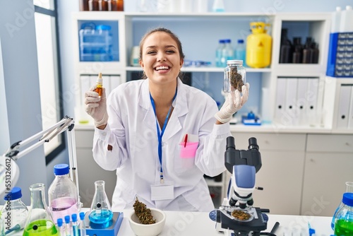 Young hispanic woman doing weed oil extraction at laboratory smiling and laughing hard out loud because funny crazy joke.
