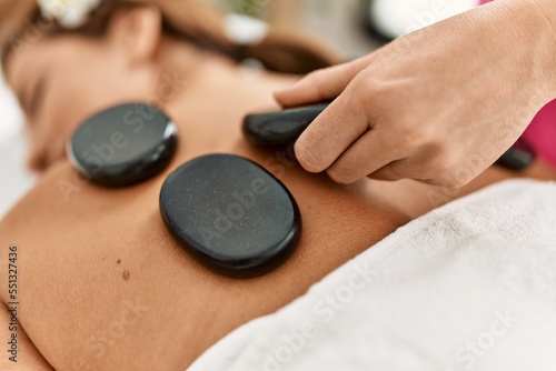 Young latin woman having back massage session using hot stones