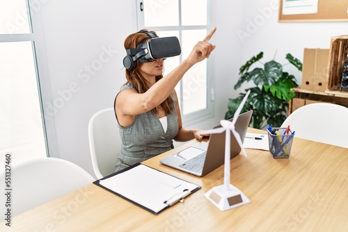 Young latin woman business worker using laptop and vr goggles at office