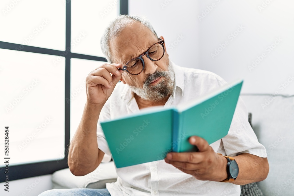 Fototapeta premium Senior grey-haired man reading book at home
