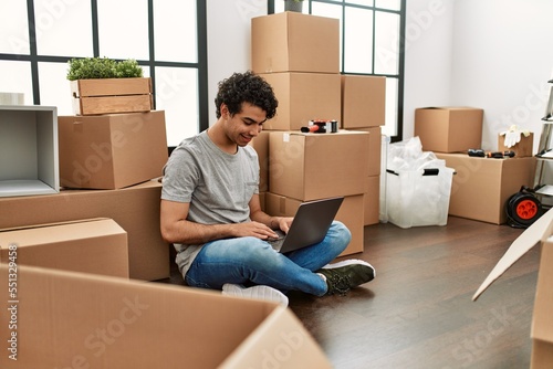 Young hispanic man using laptop sitting on the floor at new home. © Krakenimages.com