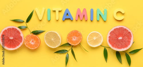 Quadro su tela Text VITAMIN C and cut citrus fruits on yellow background