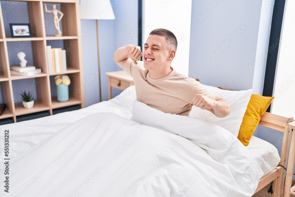 Young hispanic man waking up stretching arms at bedroom Young hispanic man waking up stretching arms at bedroom