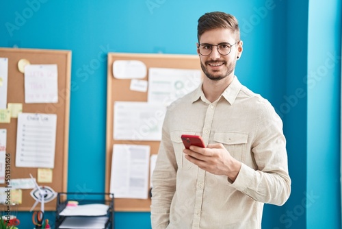 Young caucasian man business worker smiling confident using smartphone at office