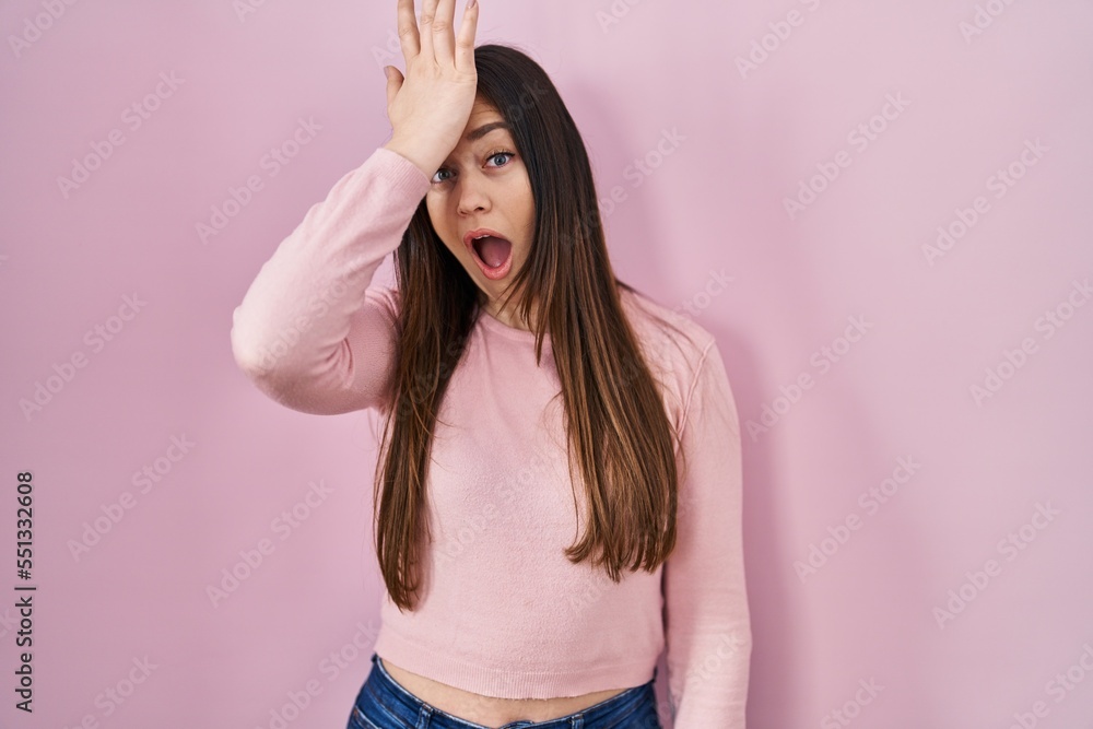 Young brunette woman standing over pink background surprised with hand on head for mistake, remember error. forgot, bad memory concept. Young brunette woman standing over pink background surprised with hand on head for mistake, remember error. forgot, bad memory concept.