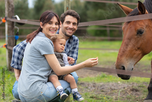 happy young family with a baby next to his horse © auremar