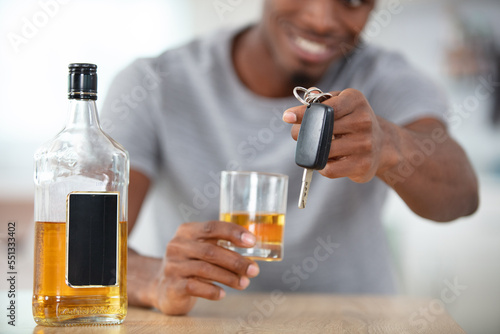 cheerful man holding alcoholic drink and passing car keys