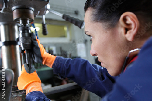 metal worker woman operating drilling machine concentrating on her job