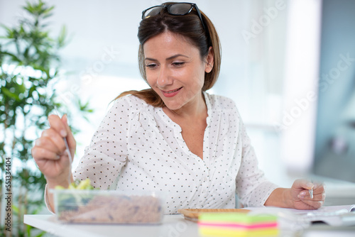 woman eating a lunch box at working table