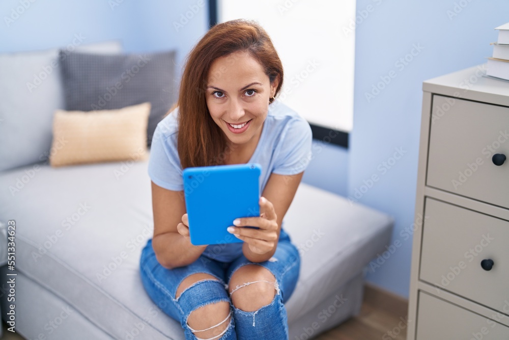 Young woman using touchpad sitting on sofa at home Young woman using touchpad sitting on sofa at home