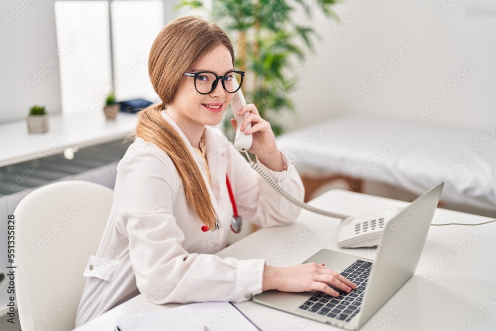 Obraz premium Young blonde woman wearing doctor uniform talking on the telephone at clinic