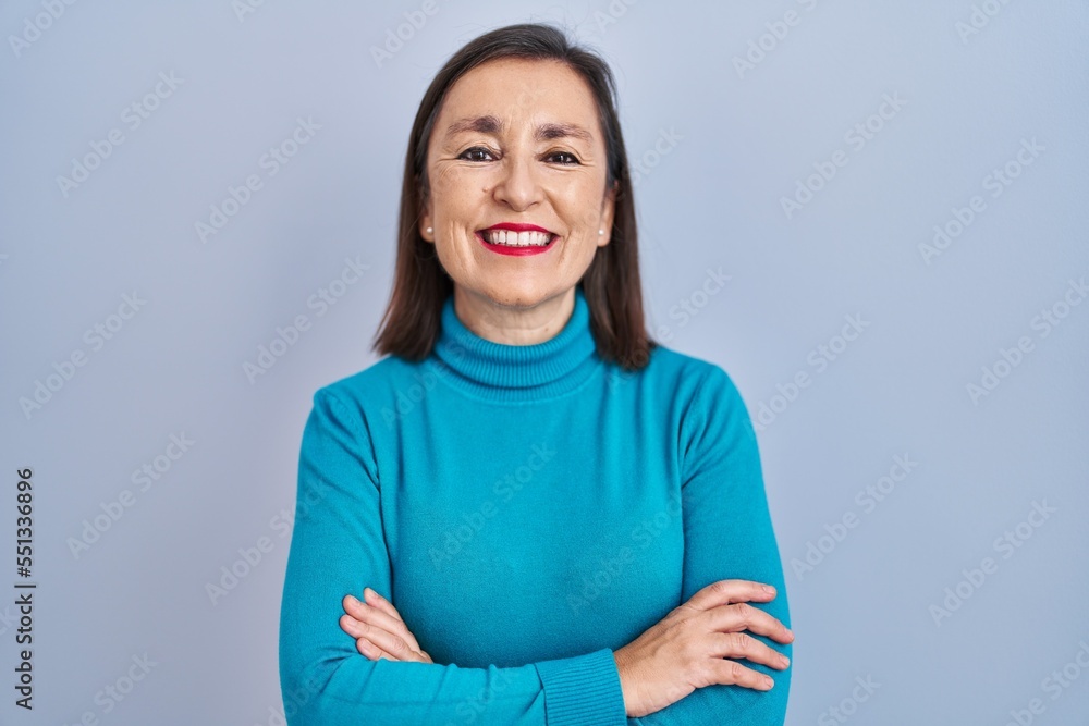Obraz premium Middle age hispanic woman standing over isolated background happy face smiling with crossed arms looking at the camera. positive person.