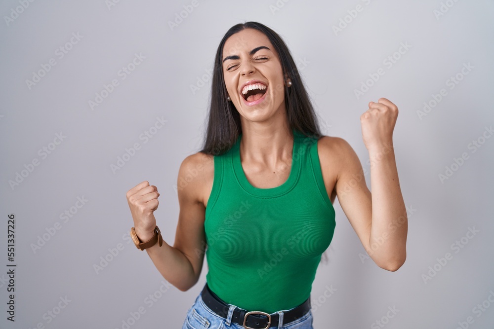 Young woman standing over isolated background celebrating surprised and amazed for success with arms raised and eyes closed. winner concept. Young woman standing over isolated background celebrating surprised and amazed for success with arms raised and eyes closed. winner concept.