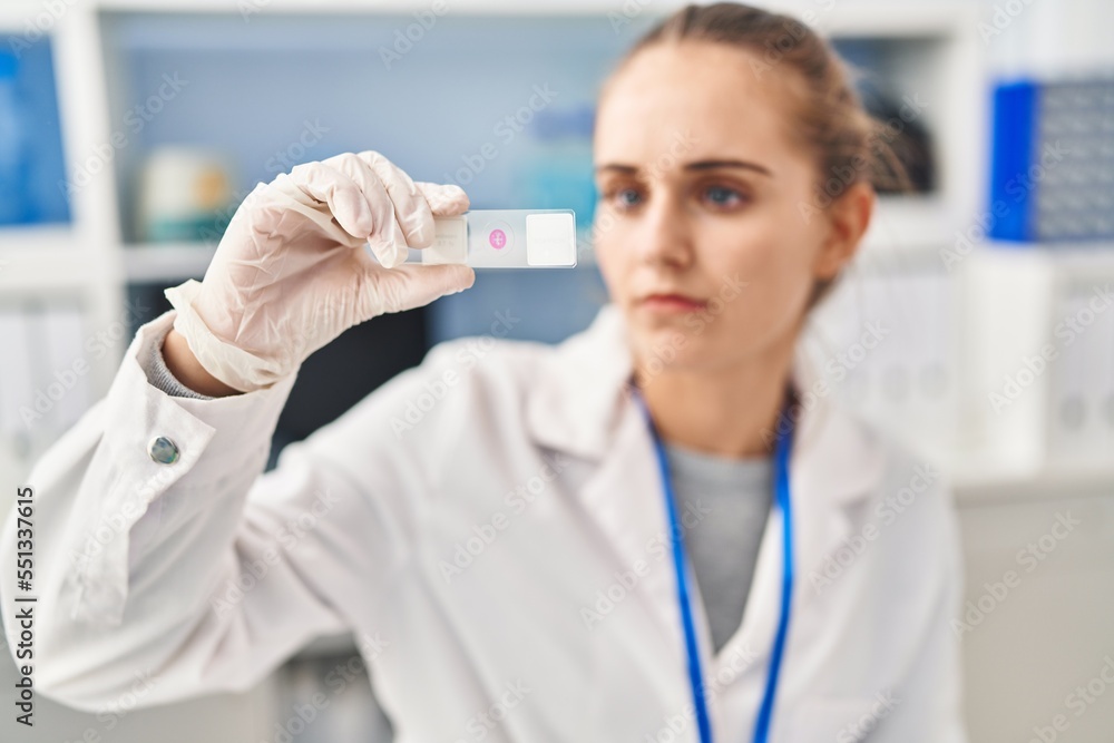 Young blonde woman wearing scientist uniform looking sample at laboratory Young blonde woman wearing scientist uniform looking sample at laboratory