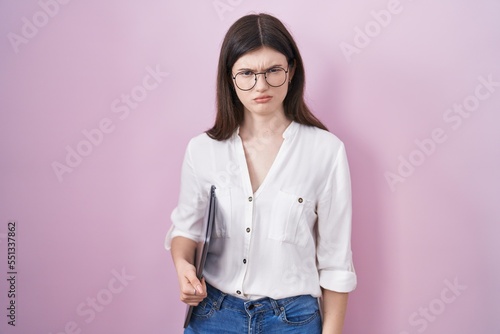 Young caucasian woman holding laptop skeptic and nervous, frowning upset because of problem. negative person.