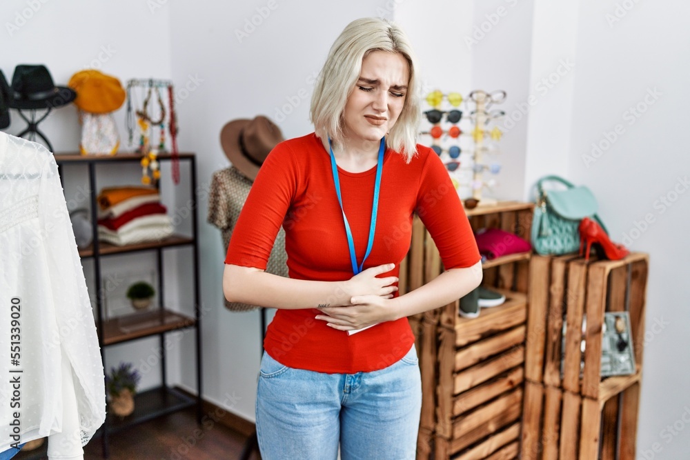 Young caucasian woman working as manager at retail boutique with hand on stomach because nausea, painful disease feeling unwell. ache concept. Young caucasian woman working as manager at retail boutique with hand on stomach because nausea, painful disease feeling unwell. ache concept.