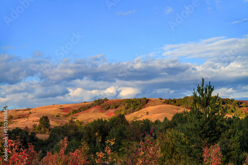 Beautiful mountain landscape. Mountains in the rays of the setting sun, in autumn.Green forest. Blue sky with beautiful clouds. park. Russia. 