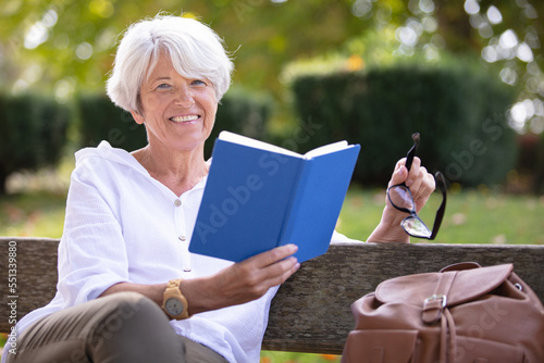 retired woman reading a book on the bench