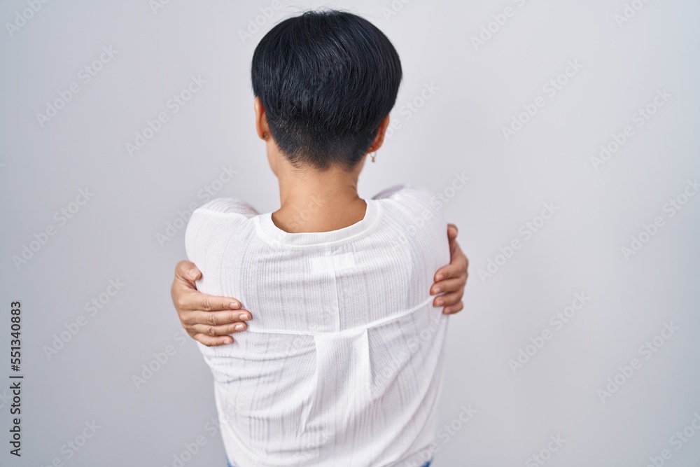 Young asian woman with short hair standing over isolated background hugging oneself happy and positive from backwards. self love and self care Young asian woman with short hair standing over isolated background hugging oneself happy and positive from backwards. self love and self care