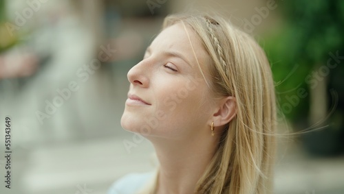 Young blonde woman breathing with closed eyes at street