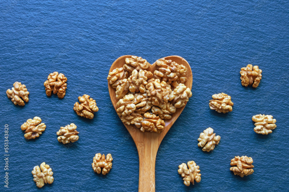 Halves of walnut kernels in heart-shaped spoon. Copy space Halves of walnut kernels in heart-shaped spoon. Copy space