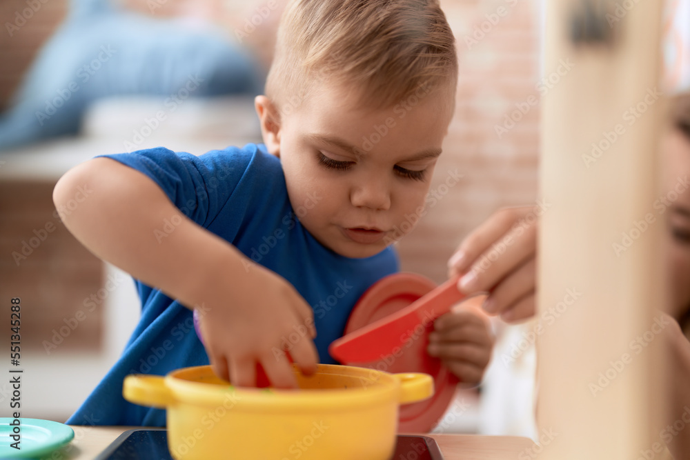 Adorable toddler playing with play kitchen standing at kindergarten Adorable toddler playing with play kitchen standing at kindergarten