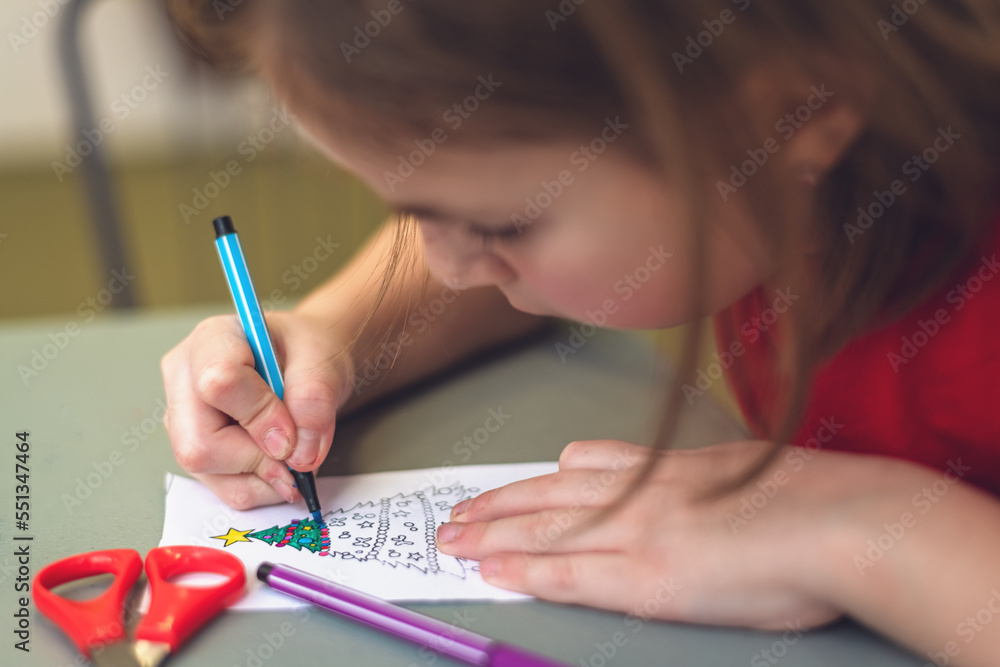 a child at a table paints a Christmas tree a child at a table paints a Christmas tree