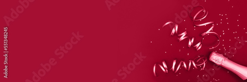 Viva Magenta color of 2023. Banner of champagne bottle with confetti stars and party streamers on trendy background. Christmas, birthday or wedding concept. Flat lay, top view, copy space, mock-up.