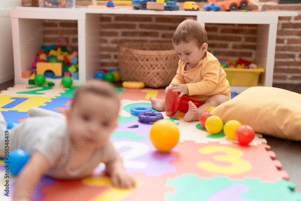 Two toddlers playing with toys sitting on floor at kindergarten Two toddlers playing with toys sitting on floor at kindergarten
