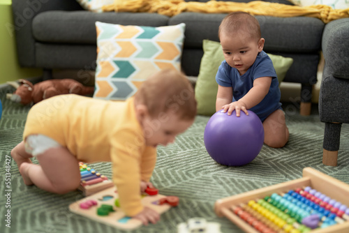 Two toddlers playing with toys sitting on floor at home