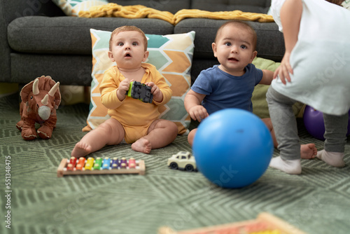 Two toddlers playing with toys sitting on floor at home