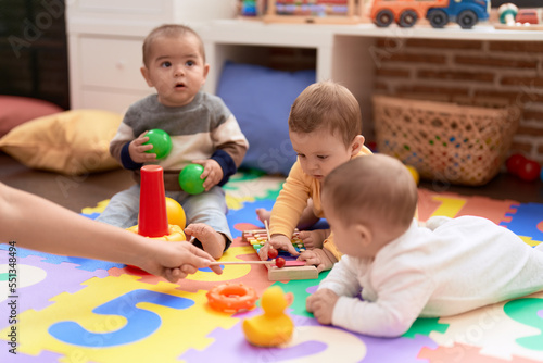 Group of toddlers playing with toys sitting on floor at kindergarten