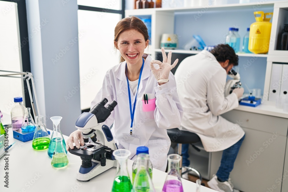 Young two people working at scientist laboratory doing ok sign with fingers, smiling friendly gesturing excellent symbol Young two people working at scientist laboratory doing ok sign with fingers, smiling friendly gesturing excellent symbol