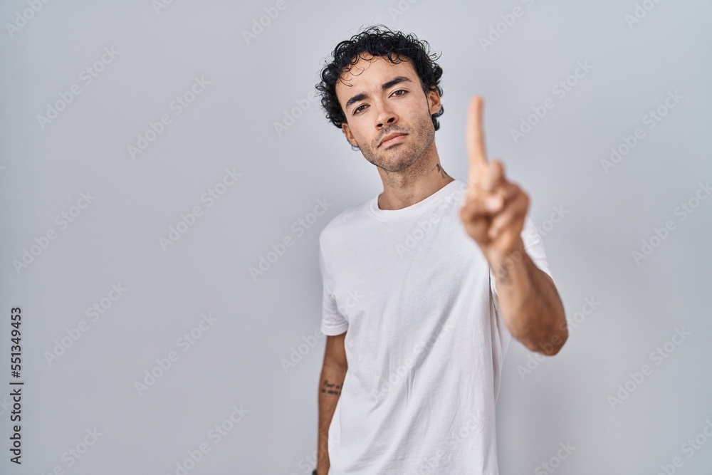 Hispanic man standing over isolated background pointing with finger up and angry expression, showing no gesture Hispanic man standing over isolated background pointing with finger up and angry expression, showing no gesture
