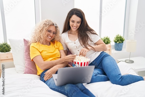 Two women mother and daughter watching movie on laptop at bedroom photo