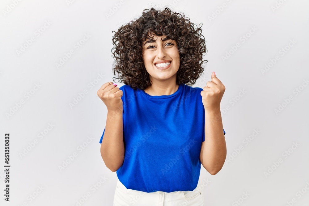 Young middle eastern woman standing over isolated background celebrating surprised and amazed for success with arms raised and open eyes. winner concept. Young middle eastern woman standing over isolated background celebrating surprised and amazed for success with arms raised and open eyes. winner concept.