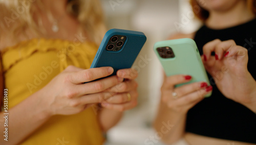 Two women using smartphone standing at home