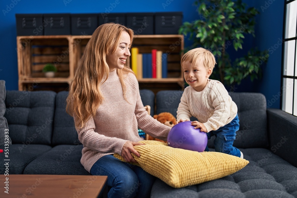 Mother and son playing with ball sitting on sofa at home Mother and son playing with ball sitting on sofa at home