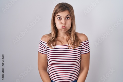 Young hispanic woman standing over isolated background puffing cheeks with funny face. mouth inflated with air, crazy expression.