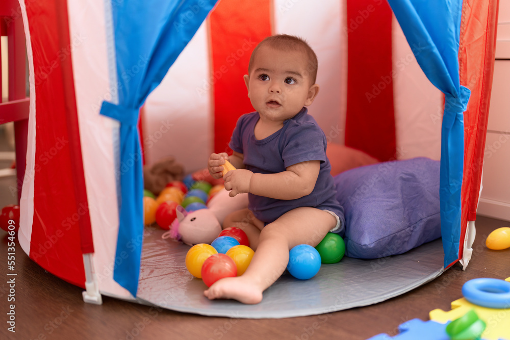Obraz premium Adorable chinese toddler playing with balls sitting inside of circus tent at home