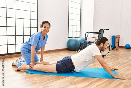 Middle age man and woman smiling confident having rehab session stretching at physiotherapy clinic