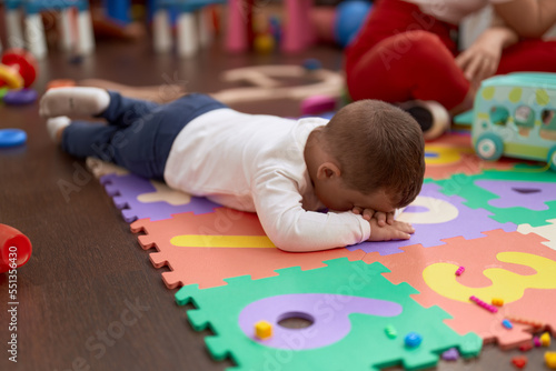 Adorable toddler lying on floor crying at kindergarten