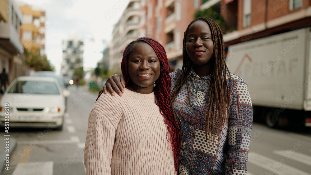 Two african american friends smiling confident hugging each other standing at street